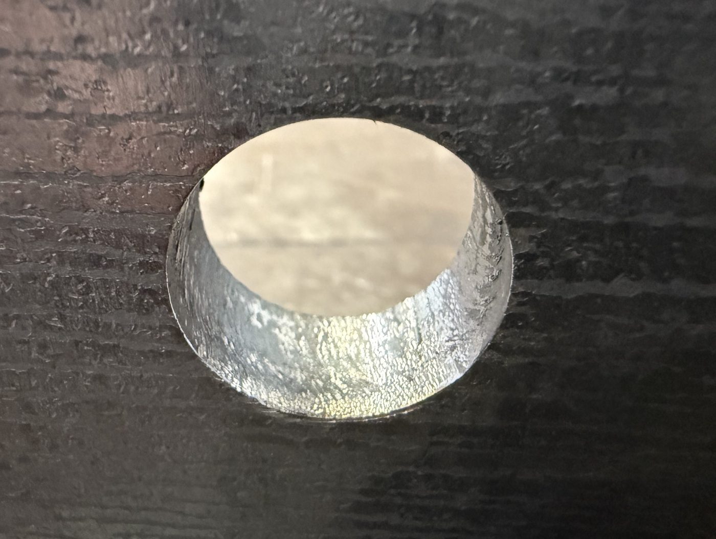Looking down into a bore cut through heavy steel plate: the bore wall is clean and the edge is free of dross and burr.